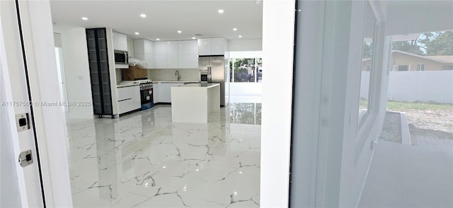 kitchen featuring modern cabinets, appliances with stainless steel finishes, light countertops, white cabinetry, and a sink