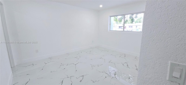 unfurnished room featuring a textured wall, marble finish floor, recessed lighting, and baseboards