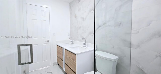 bathroom featuring toilet, marble finish floor, double vanity, and a sink