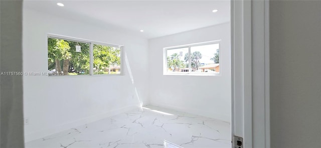 empty room with baseboards, marble finish floor, recessed lighting, and a healthy amount of sunlight