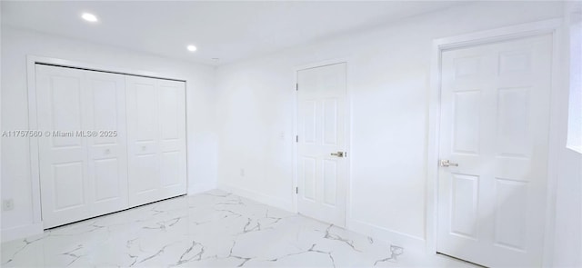 unfurnished bedroom featuring a closet, recessed lighting, marble finish floor, and baseboards