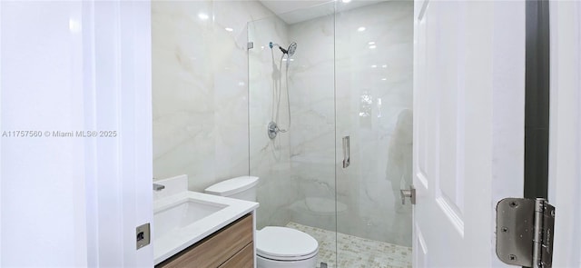 bathroom with vanity, a marble finish shower, toilet, and tile walls