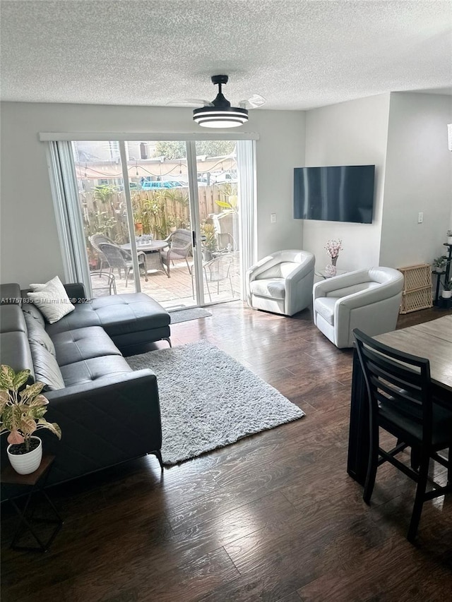 living area with a wealth of natural light, a textured ceiling, and wood finished floors