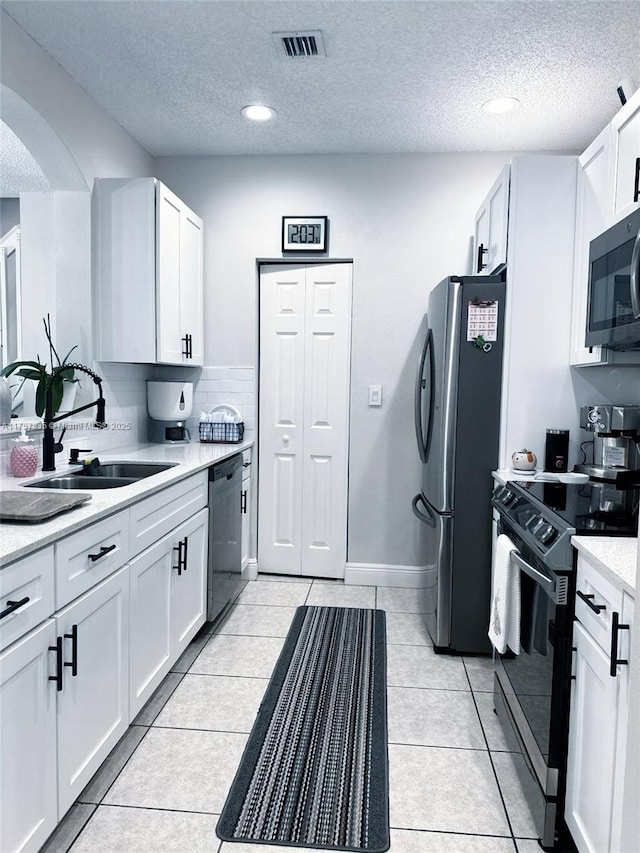 kitchen featuring black appliances, light tile patterned floors, light countertops, and a sink