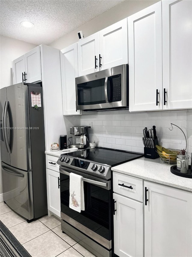 kitchen featuring light tile patterned floors, white cabinetry, stainless steel appliances, and backsplash