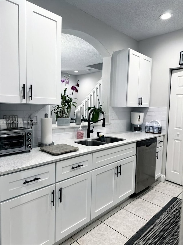 kitchen featuring white cabinets, dishwasher, a textured ceiling, a sink, and light tile patterned flooring