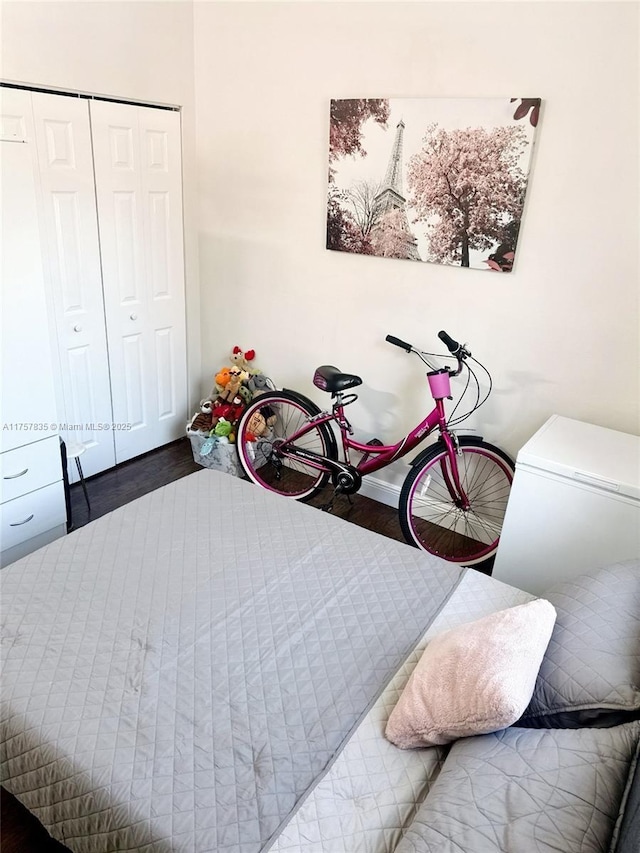 bedroom with a closet, fridge, and wood finished floors