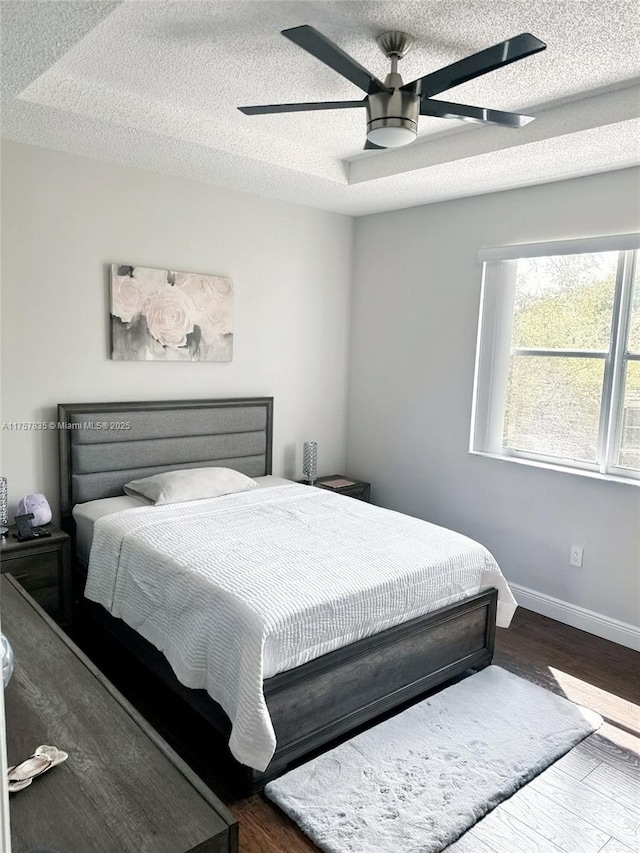 bedroom with a ceiling fan, a textured ceiling, baseboards, and wood finished floors