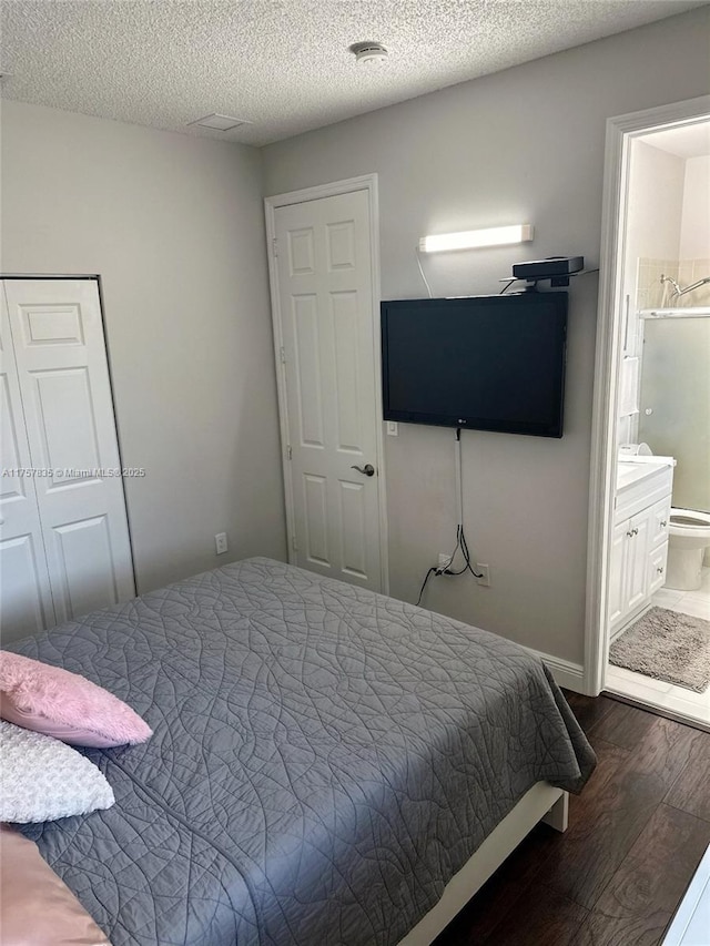 bedroom with a closet, a textured ceiling, wood finished floors, and ensuite bathroom