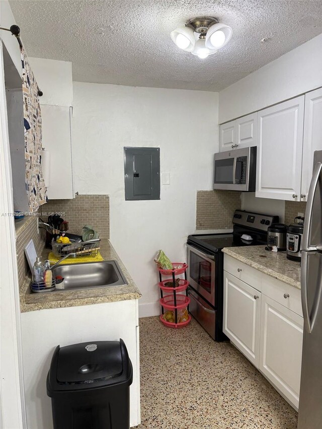 kitchen with appliances with stainless steel finishes, a sink, electric panel, and white cabinets