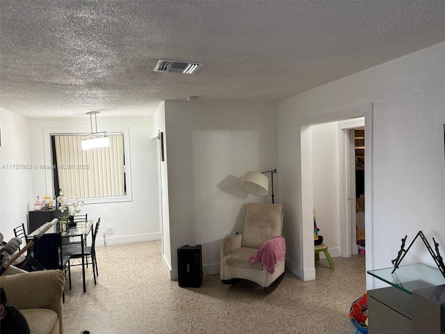 interior space with baseboards, visible vents, a textured ceiling, and speckled floor