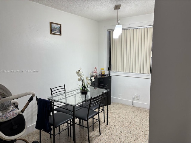 dining area featuring a textured ceiling, speckled floor, and baseboards