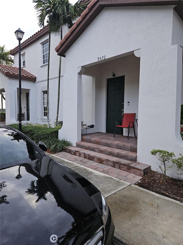 entrance to property with a tile roof and stucco siding