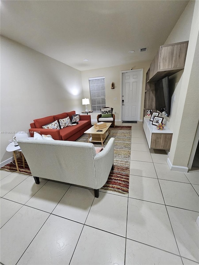 living room with light tile patterned floors, visible vents, and baseboards