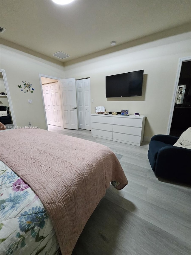 bedroom with light wood-style flooring, visible vents, and baseboards