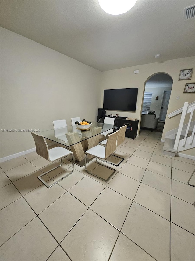 dining area with visible vents, arched walkways, baseboards, and light tile patterned flooring