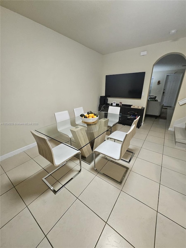 dining room featuring baseboards, arched walkways, and light tile patterned flooring