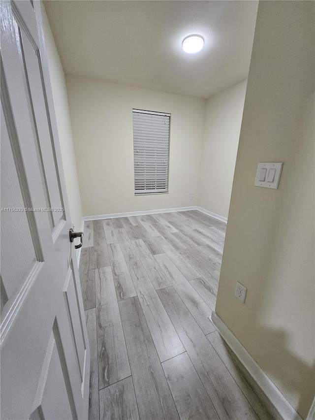 spare room with baseboards and wood finished floors