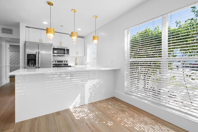 kitchen with visible vents, wood finished floors, stainless steel appliances, light countertops, and white cabinetry