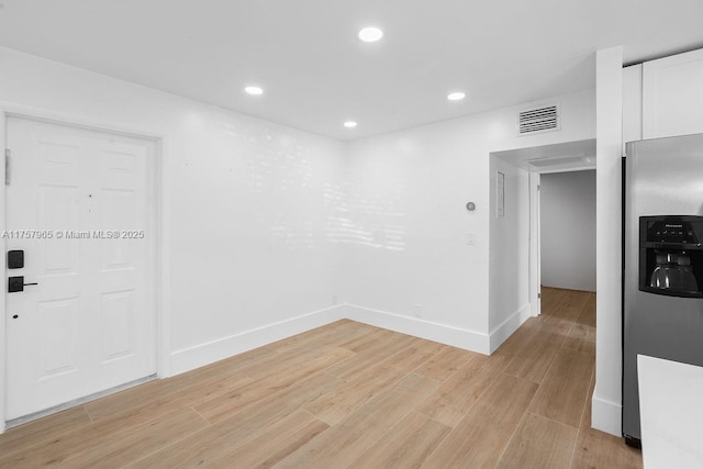 unfurnished room with light wood-type flooring, visible vents, baseboards, and recessed lighting