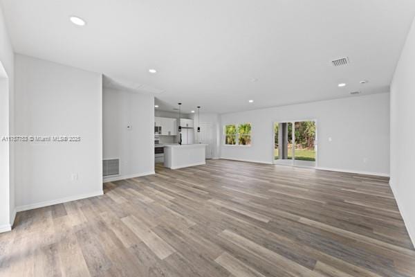 unfurnished living room with baseboards, visible vents, wood finished floors, and recessed lighting