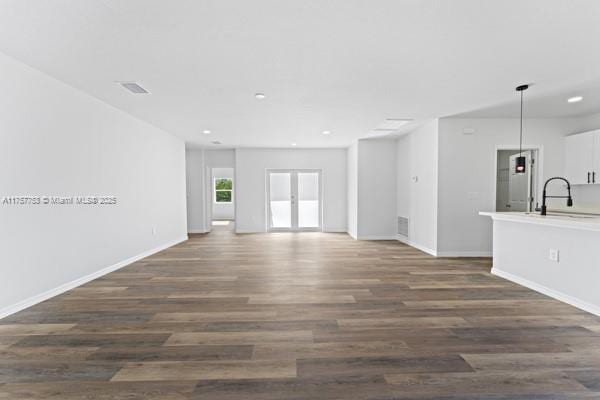 unfurnished living room featuring a sink, visible vents, baseboards, french doors, and dark wood-style floors