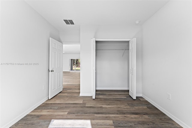 unfurnished bedroom with baseboards, a closet, visible vents, and wood finished floors