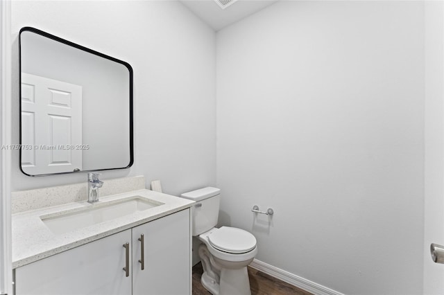 bathroom with toilet, wood finished floors, vanity, and baseboards