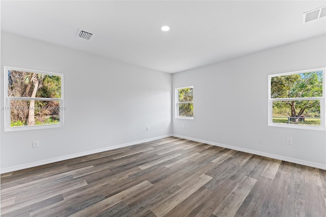 unfurnished room featuring wood finished floors, visible vents, and baseboards