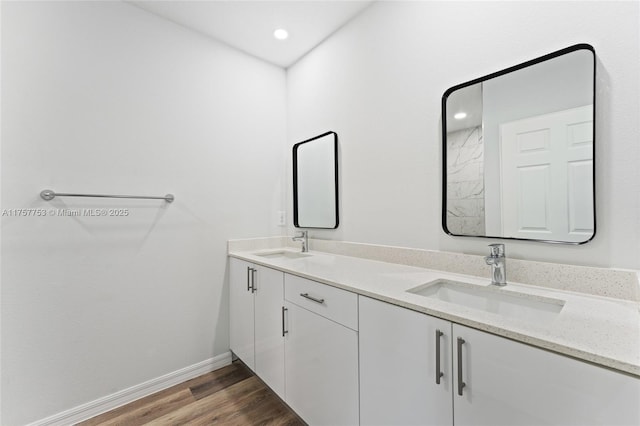 bathroom with double vanity, baseboards, a sink, and wood finished floors