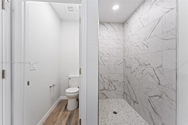 bathroom featuring toilet, wood finished floors, visible vents, baseboards, and a stall shower