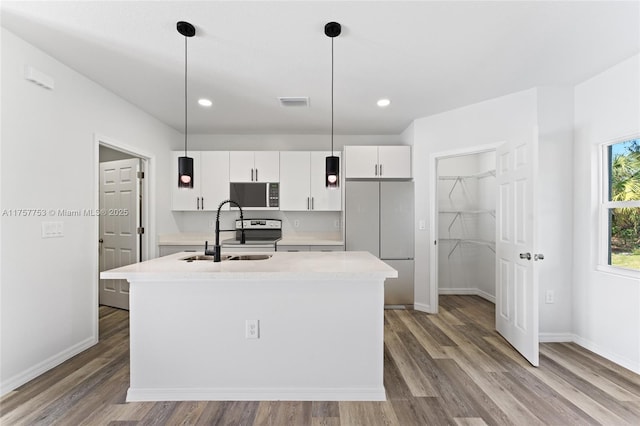 kitchen featuring light countertops, white cabinetry, a sink, an island with sink, and wood finished floors