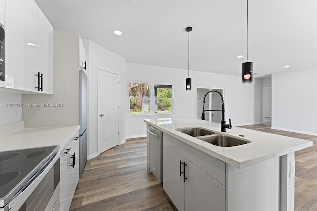 kitchen featuring appliances with stainless steel finishes, light wood-type flooring, a kitchen island with sink, and a sink