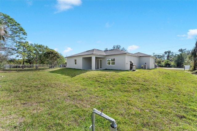 back of house with a lawn and stucco siding