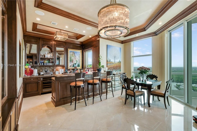 bar featuring an inviting chandelier, visible vents, a raised ceiling, and ornamental molding