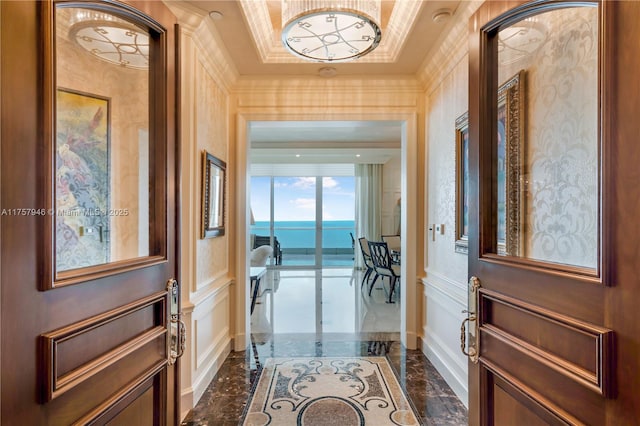 interior space featuring marble finish floor, a decorative wall, a raised ceiling, and crown molding