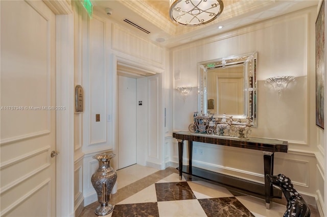 corridor featuring crown molding, a raised ceiling, visible vents, and a decorative wall