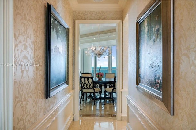 corridor with a chandelier, crown molding, and wallpapered walls