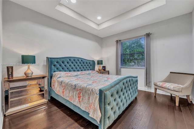 bedroom with wood-type flooring, baseboards, a raised ceiling, and recessed lighting