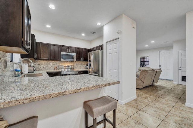 kitchen with dark brown cabinetry, visible vents, decorative backsplash, stainless steel appliances, and a sink