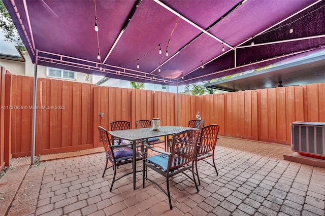 view of patio featuring outdoor dining space, fence private yard, cooling unit, and visible vents