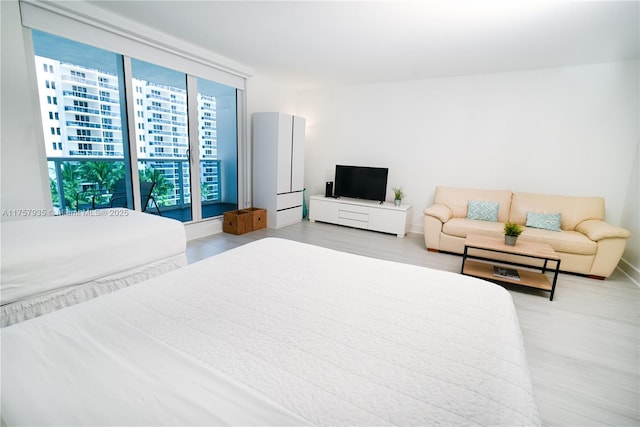 bedroom featuring light wood-type flooring and floor to ceiling windows