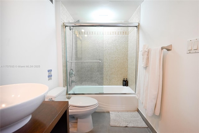 bathroom featuring vanity, combined bath / shower with glass door, tile patterned flooring, and toilet