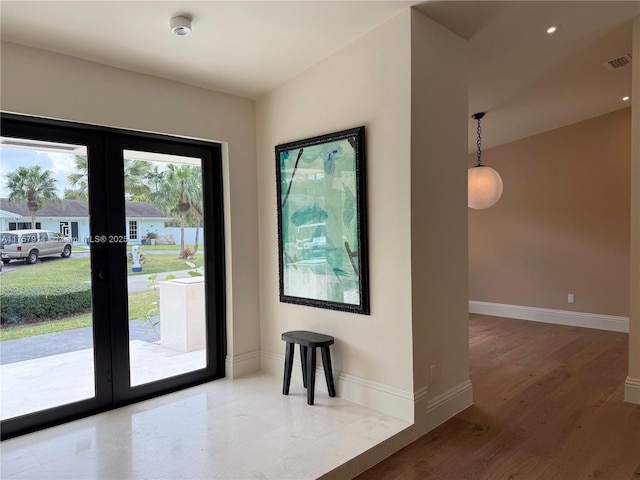 doorway featuring visible vents, baseboards, wood finished floors, and french doors