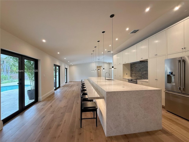 kitchen featuring a sink, appliances with stainless steel finishes, light wood-type flooring, decorative backsplash, and modern cabinets