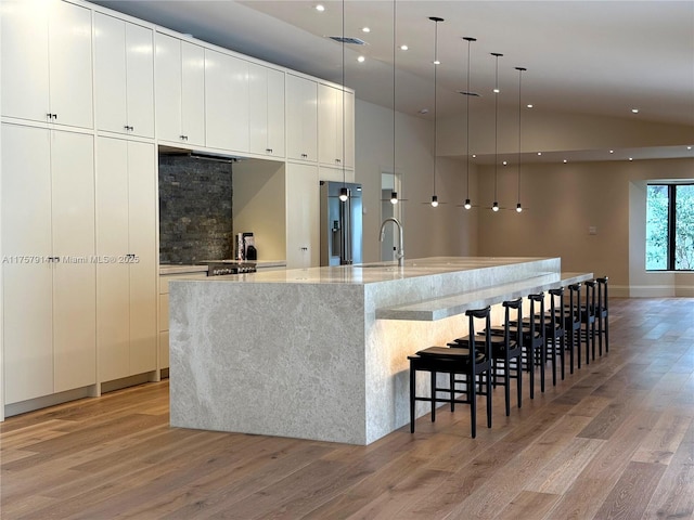 kitchen featuring light wood-type flooring, stainless steel fridge, a large island, and modern cabinets