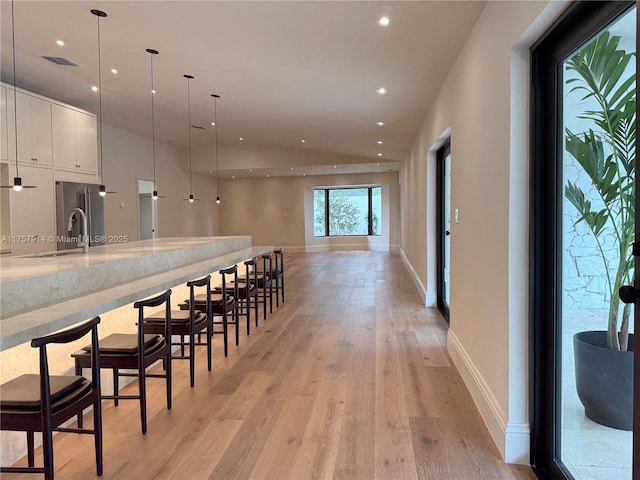 kitchen featuring visible vents, modern cabinets, light wood-type flooring, white cabinetry, and a sink