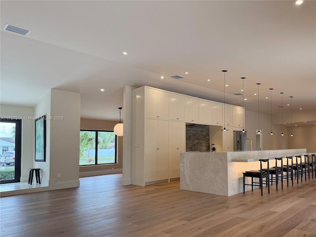 kitchen with light wood finished floors, white cabinetry, modern cabinets, and visible vents