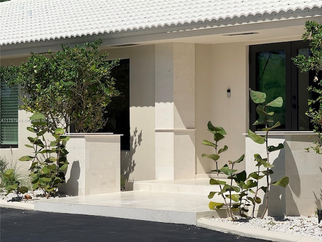 view of exterior entry with a tiled roof and stucco siding