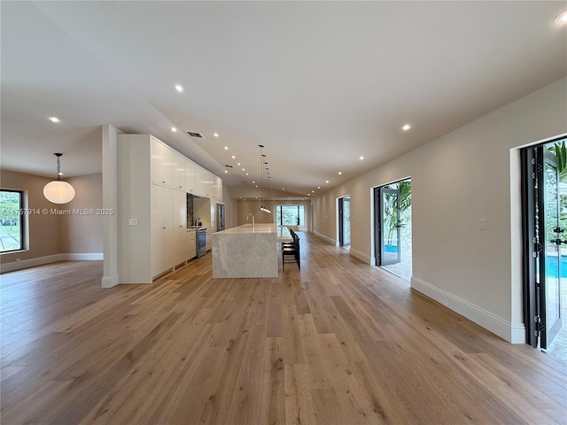 unfurnished living room featuring light wood-style floors, plenty of natural light, and a sink